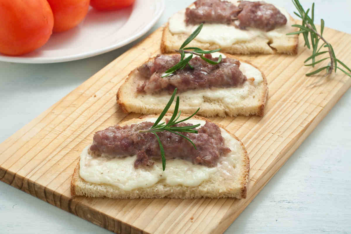 tagliere di legno con sopra la ricetta del giorno, i crostini con salsiccia e stracchino