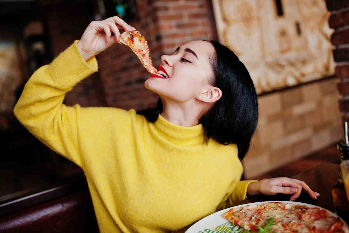 donna mangia una fetta di pizza