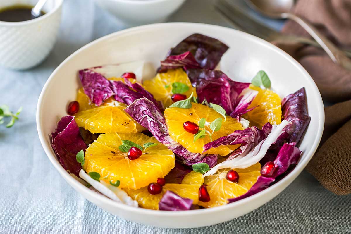 Scodella con all'interno un'insalata con radicchio, arancia e melograno