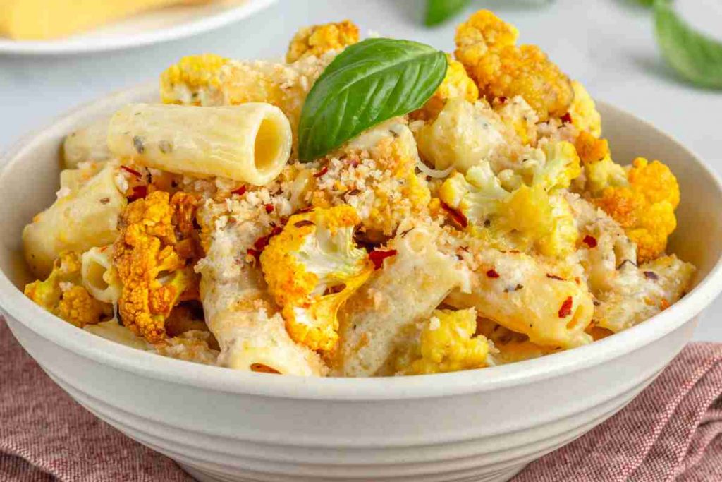 Pasta con il cavolfiore in un piatto decorata con una foglia di basilico
