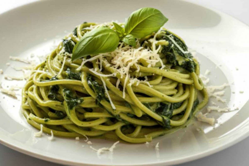 una porzione di spaghetti con il cavolo nero decorata con formaggio grattugiato e foglie di basilico
