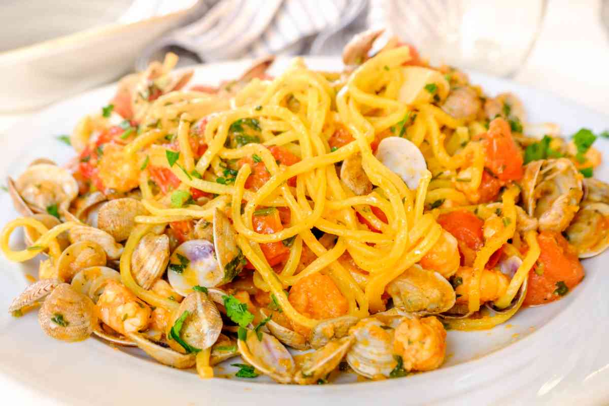 piatto con spaghetti alla chitarra conditi con vongole e pomodoro