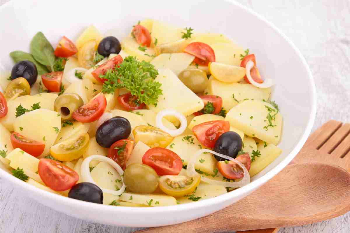 Insalata pantesca con patate, pomodori olive e cipolle in un piatto fondo