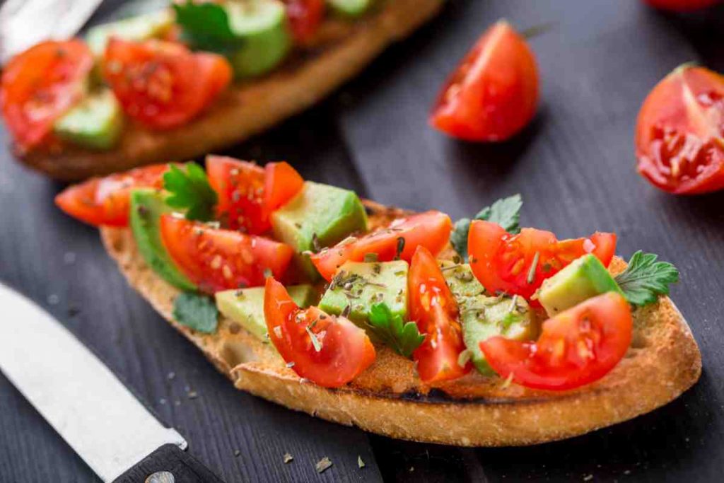 Bruschetta con avocado e pomodori sul tagliere