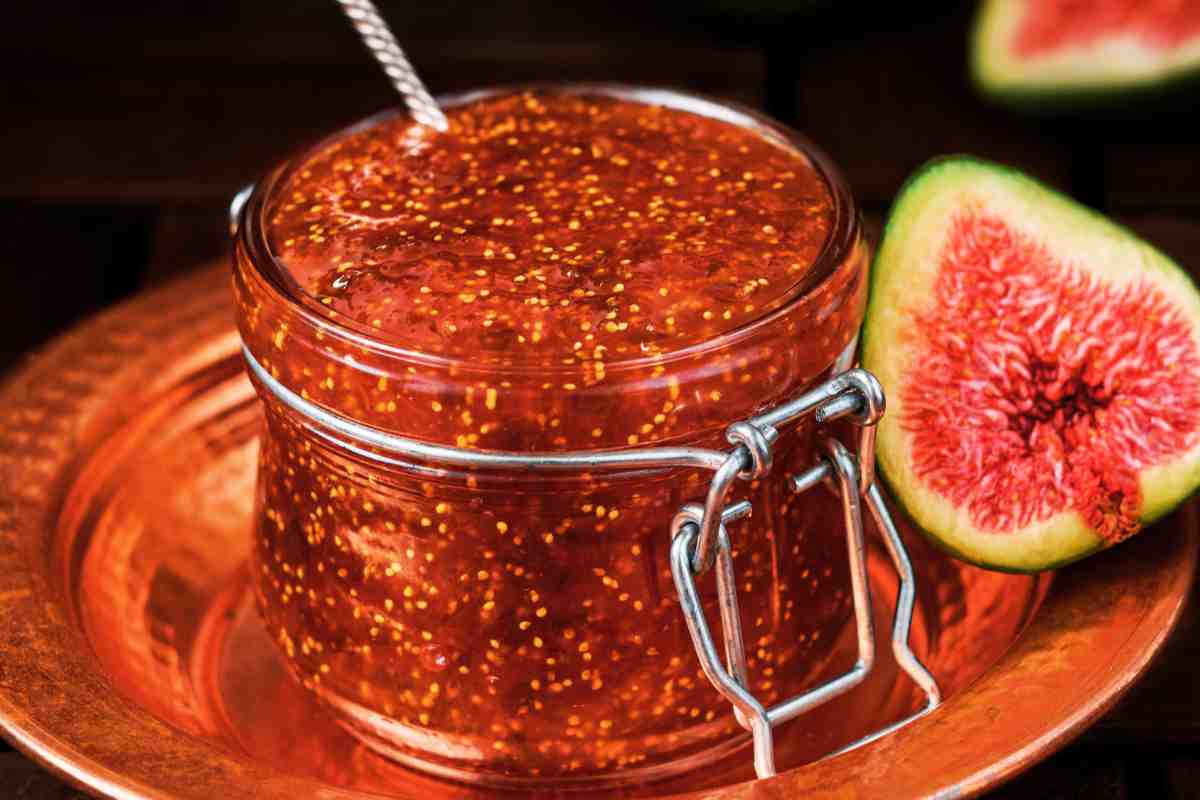 Marmellata di fichi senza zucchero in un barattolo di vetro con dietro dei fichi tagliati a metà