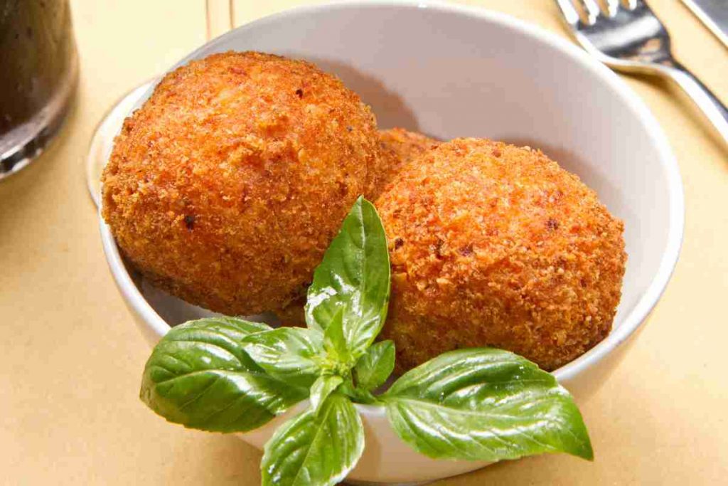 Arancini con ragù di gamberi fritti con foglie di basilico