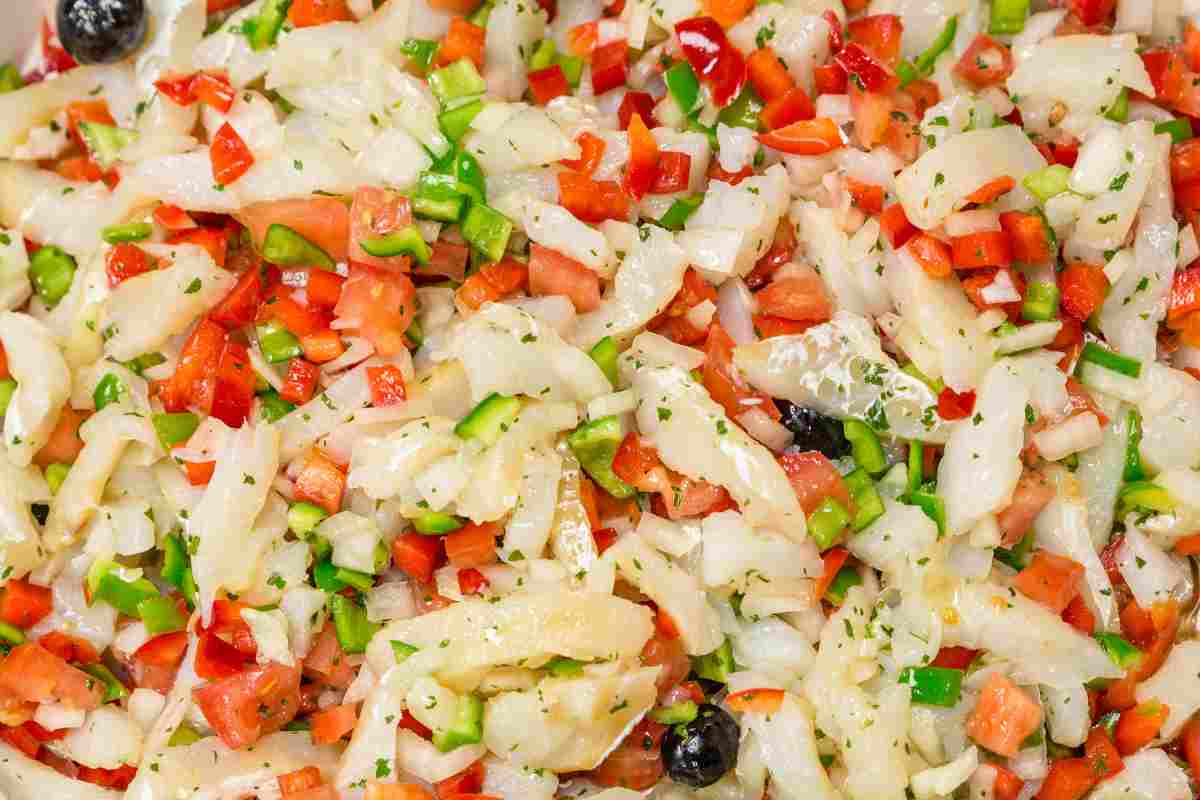 primo piano di un piatto di baccalà all'insalata con pomodoro e olive