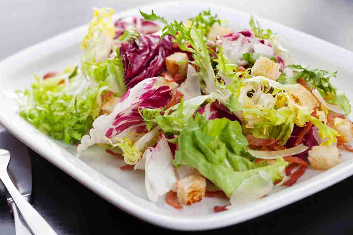 Caesar Salad con speck in piatto bianco