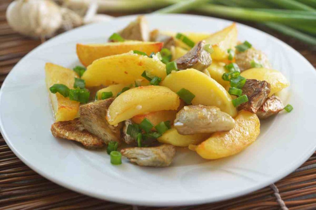 Un piatto bianco con i carciofi e patate al forno 