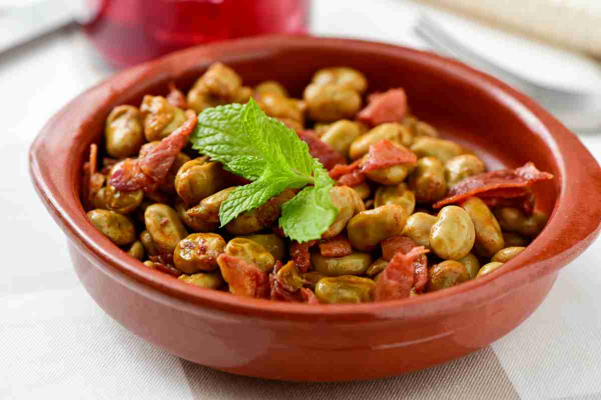 Ciotola di coccio con fave in umido con guanciale e foglia di menta in cima