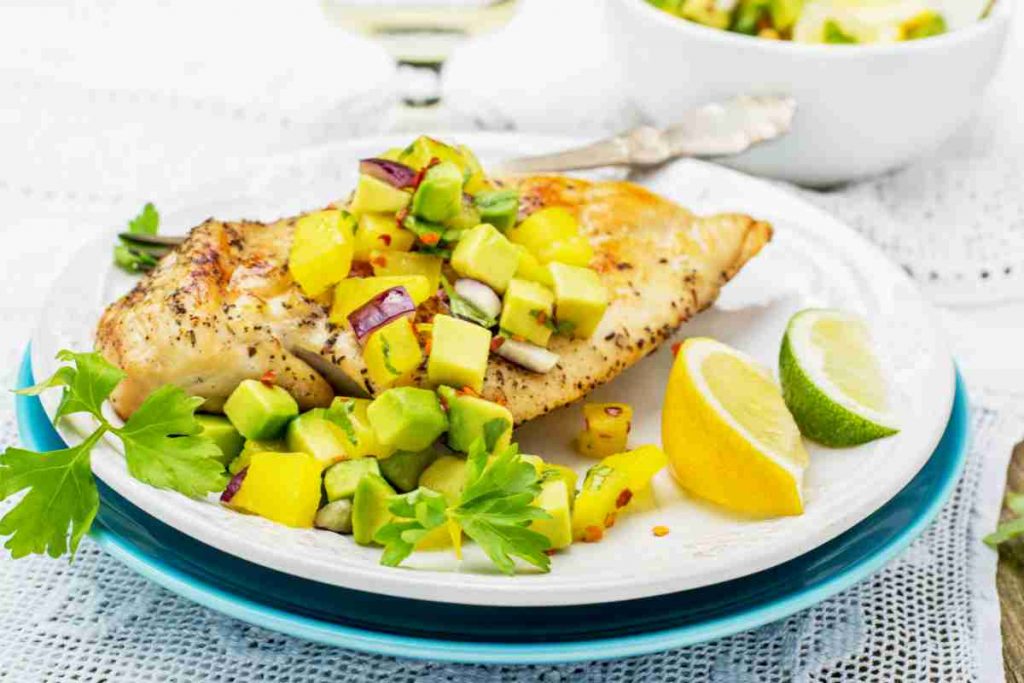 Piatto con dentro un petto di pollo alla griglia con salsa al mango 