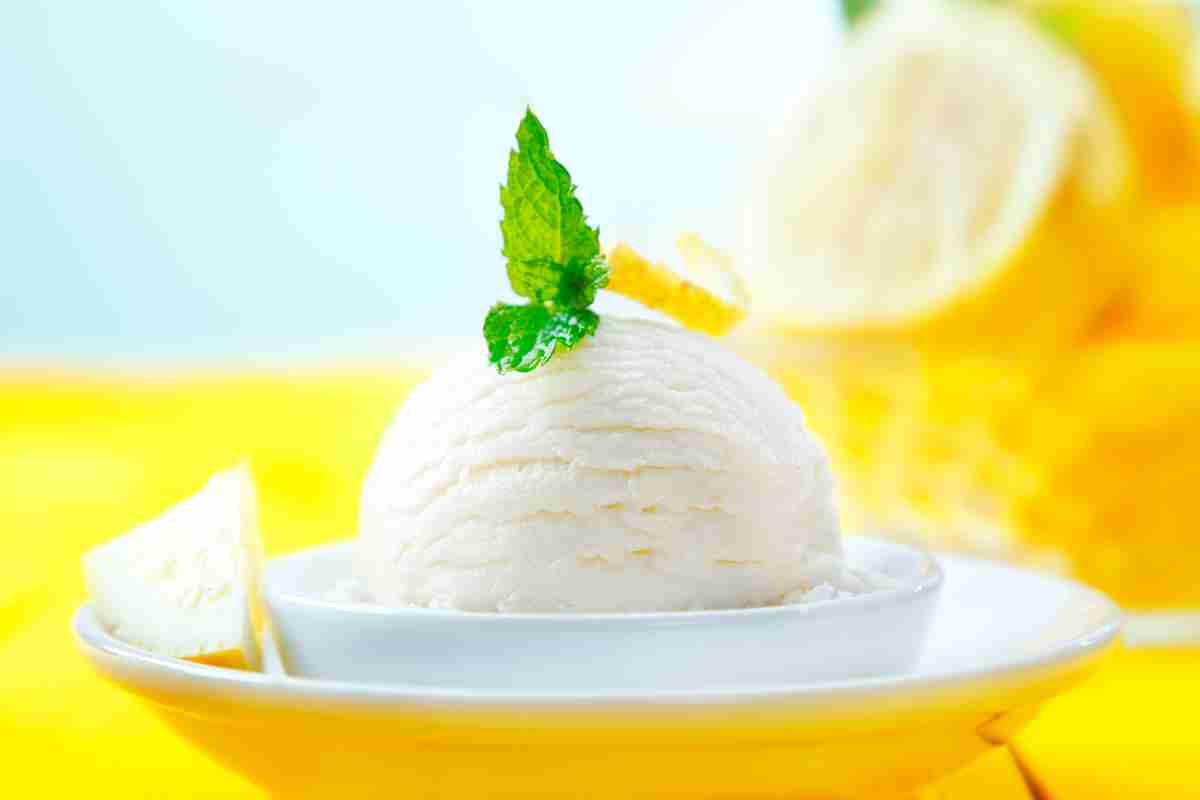 coppetta bianca su piatto giallo con pallina di sorbetto al limone