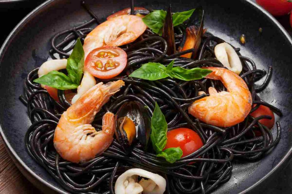 piatto nero con gli spaghetti di riso venere alla pescatora per la festa della mamma