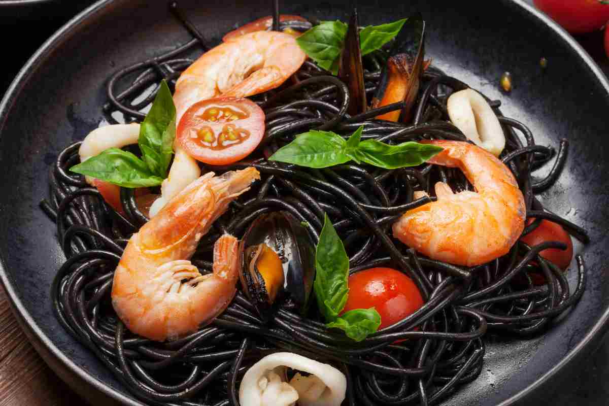 piatto nero con gli spaghetti di riso venere alla pescatora