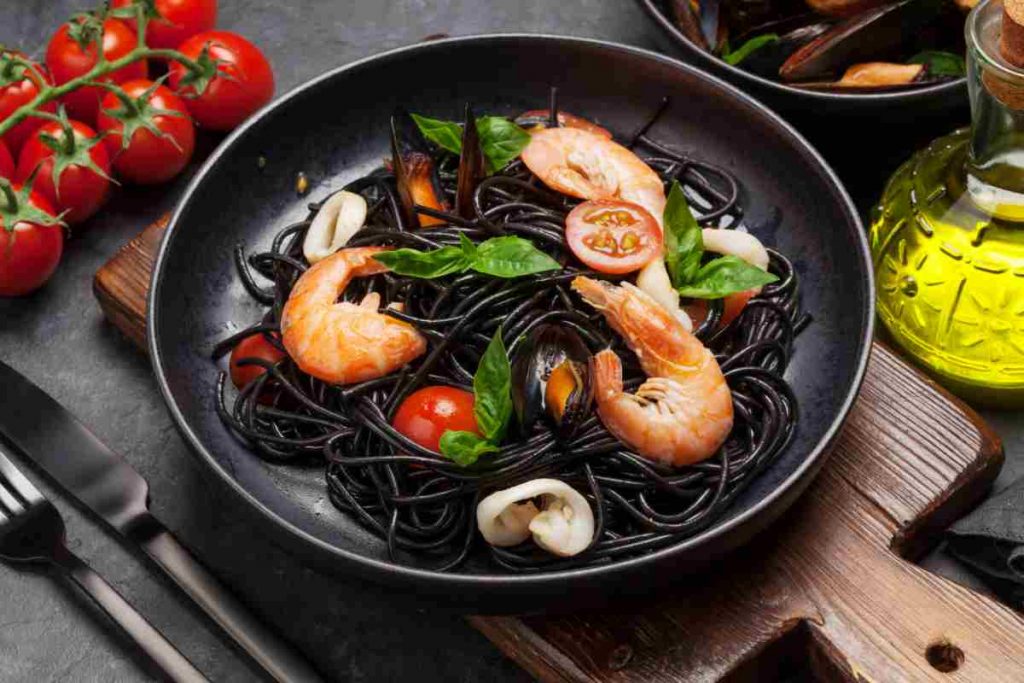 Vista dall'alto di spaghetti neri di riso venere alla pescatora con gamberi cozze e totani