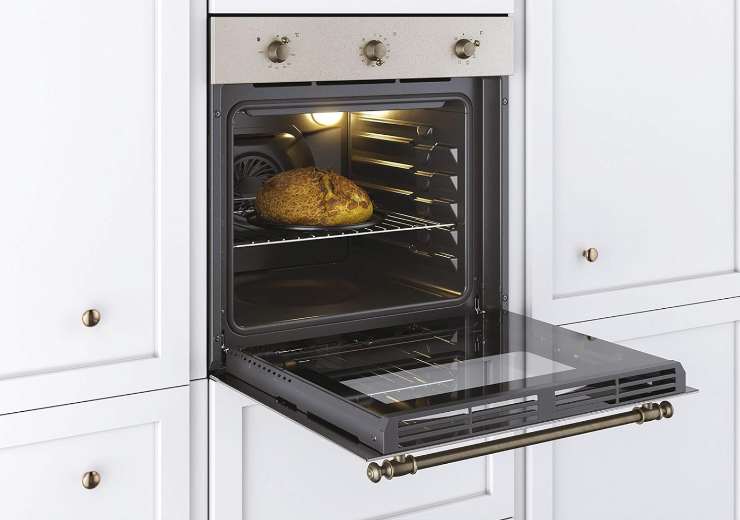 forno a incasso dentro a una cucina col portellone spalancato e al suo interno del pane