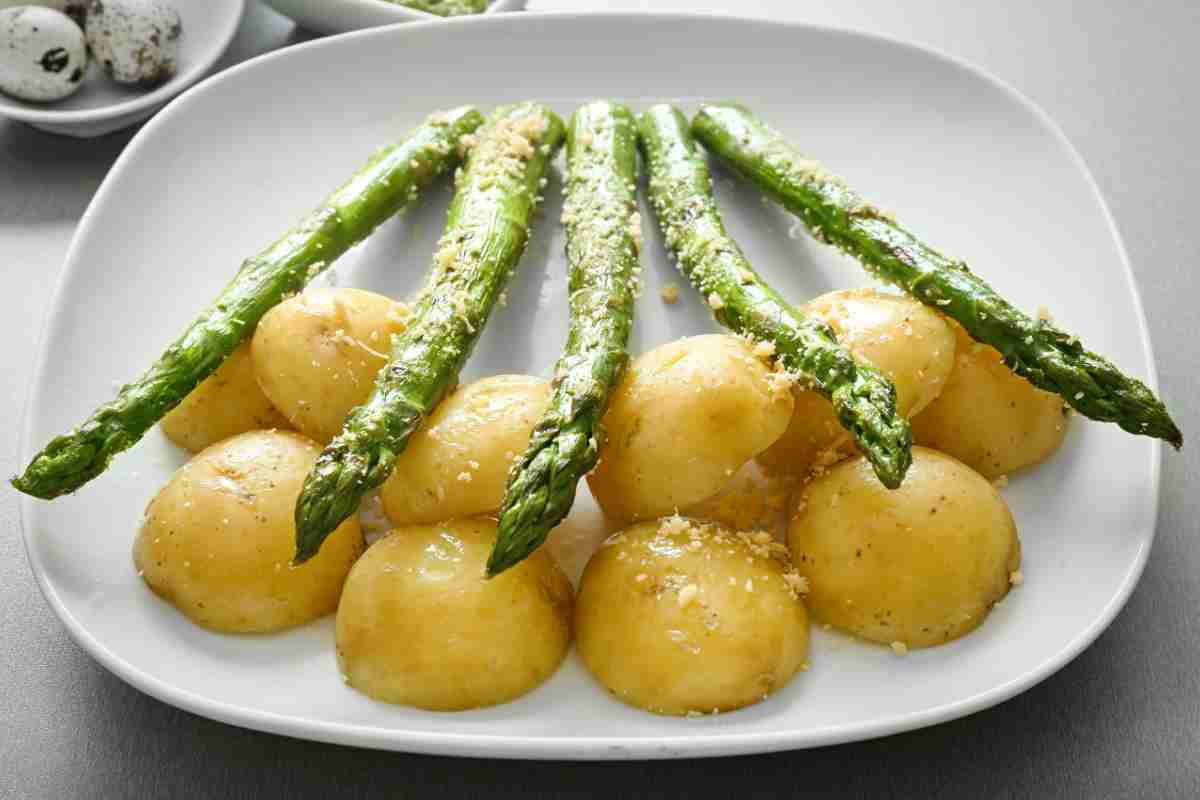 Asparagi sistemati sulle patate tagliate a metà, il tutto cotto in forno e poi messo in piatto bianco