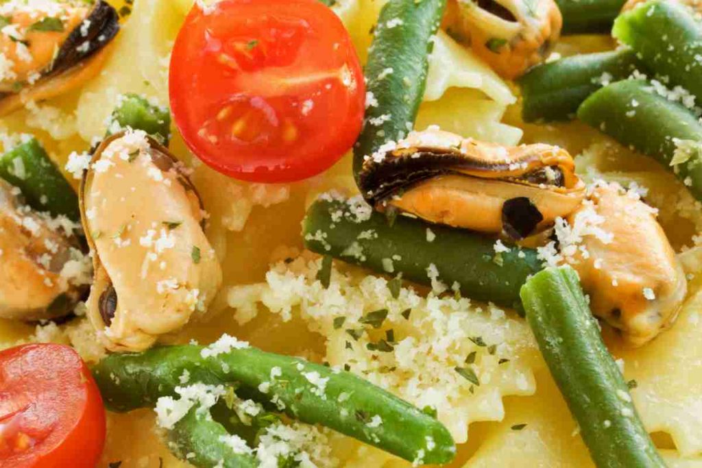 primo piano di un'insalata di pasta con le cozze arricchita con pomodorini e fagiolini