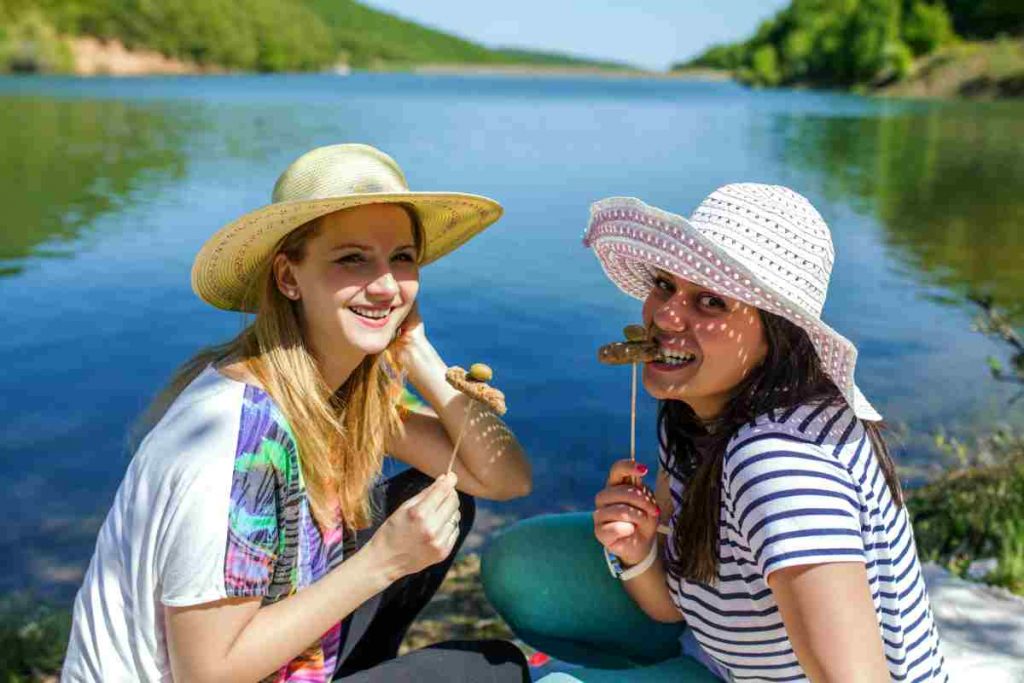 ragazze mangiano pesce con il lago sullo sfondo