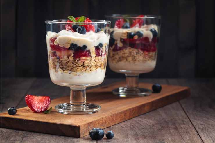 bicchiere con parfait di yogurt, avena e frutti di bosco per la merenda sana