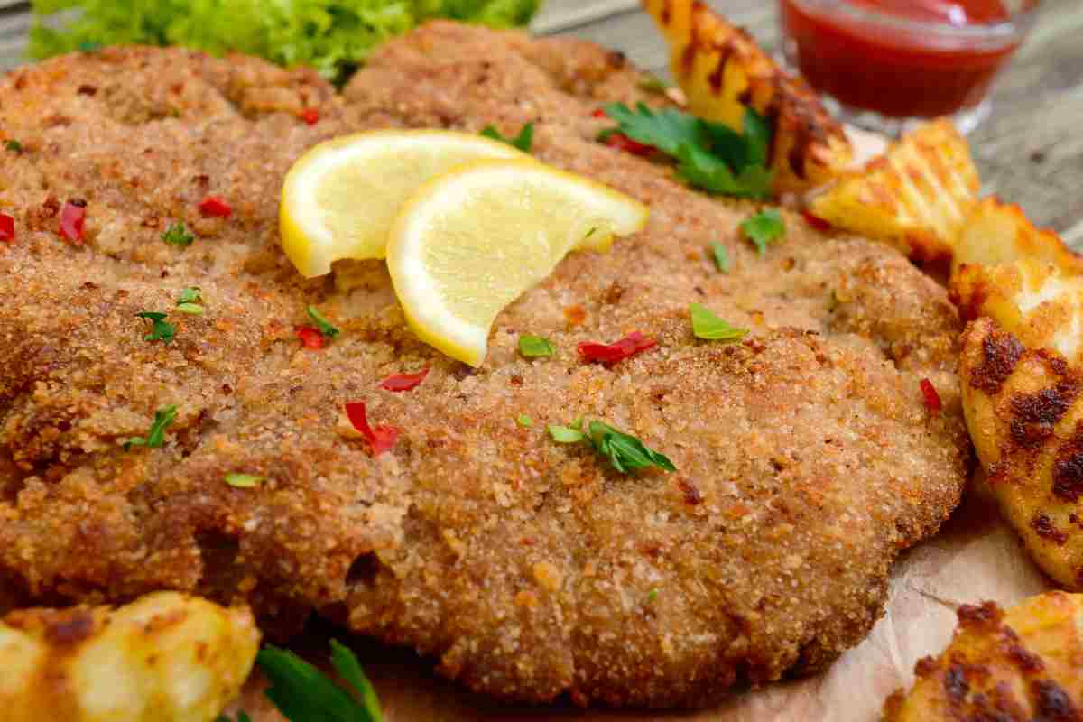 una cotoletta alla palermitana vista da vicino guarnita con fette di limone
