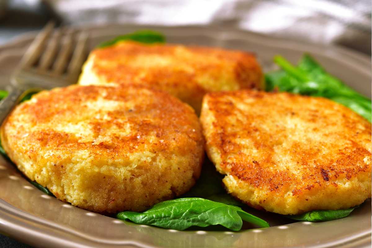 Cotoletta di cous cous in un piatto con foglie di basilico