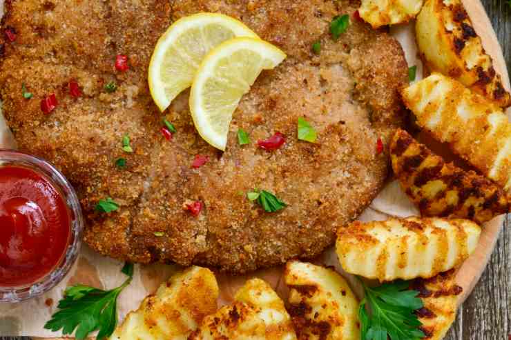 Cotolette alla palermitana in un piatto con patate di contorno viste dall'alto