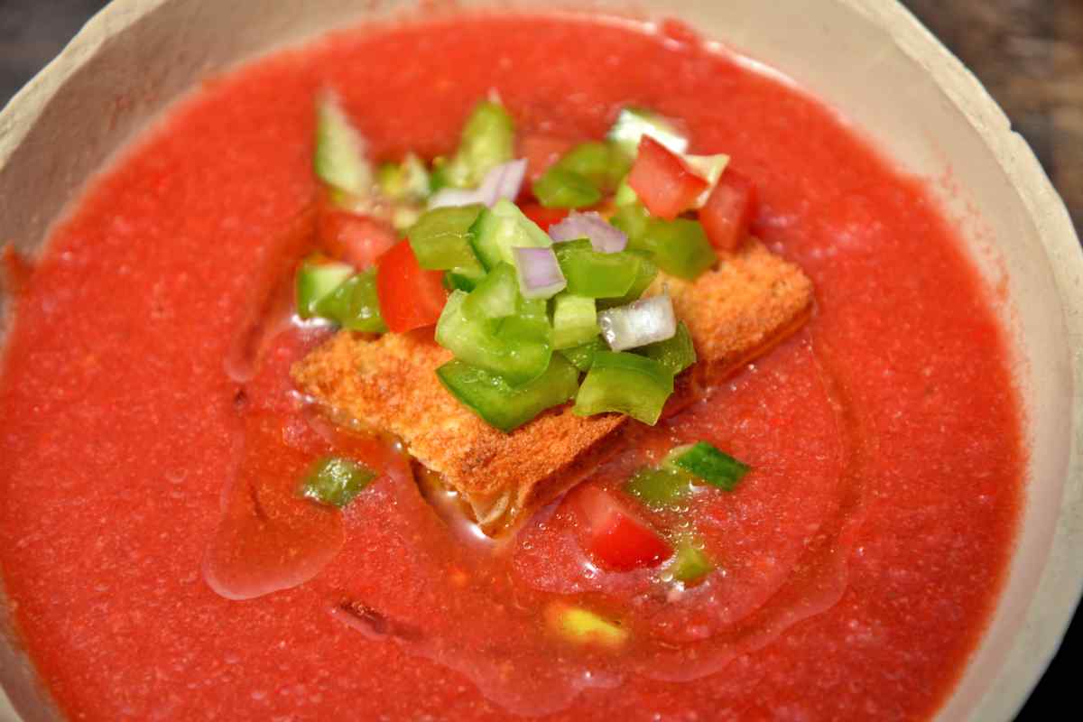 ciotola con gazpacho guarnito con crostini e peperoni a pezzettini