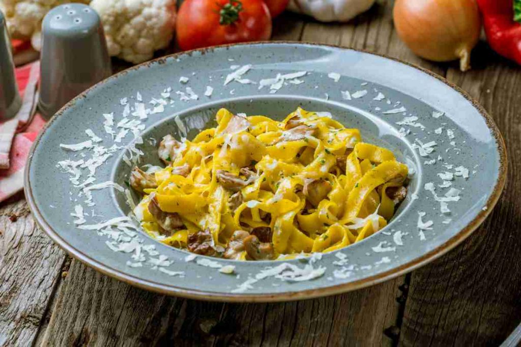 Tagliatelle ai funghi porcini in un piatto su un tavolo di legno