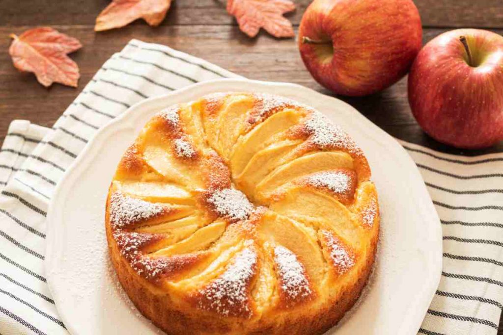 Torta alle mele in un vassoio con mele sullo sfondo