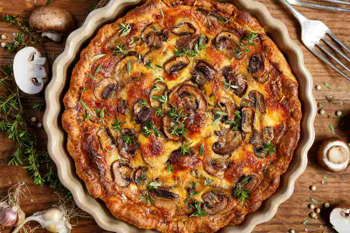 Torta salata funghi e pancetta in una pirofila tonda vista dall'alto