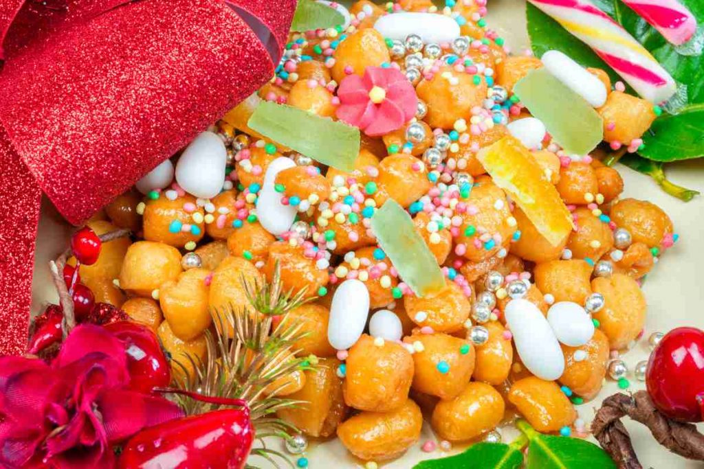 un piatto con tanti struffoli napoletani decorati con confetti e frutta candita