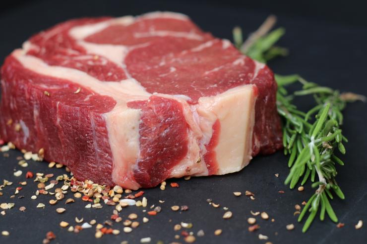 bistecca cruda con accanto un rametto di rosmarino