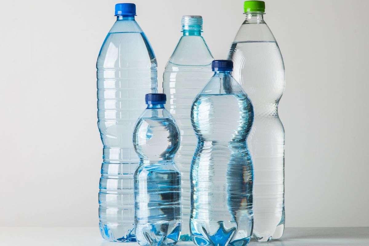 5 bottiglie di plastica con acqua dentro su un tavolo
