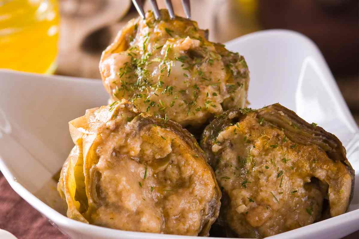 Carciofi ripieni in un piatto con una forchetta infilzata