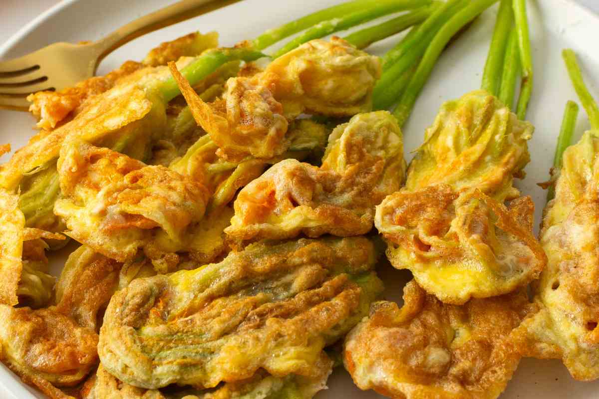 Fiori di zucca in pastella al forno in un piatto con una forchetta vicino