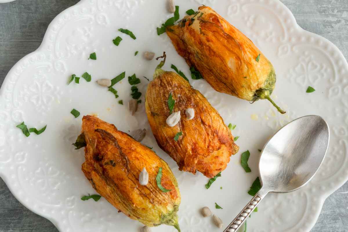 Fiori di zucca ripieni al forno in un piatto visti dall'alto