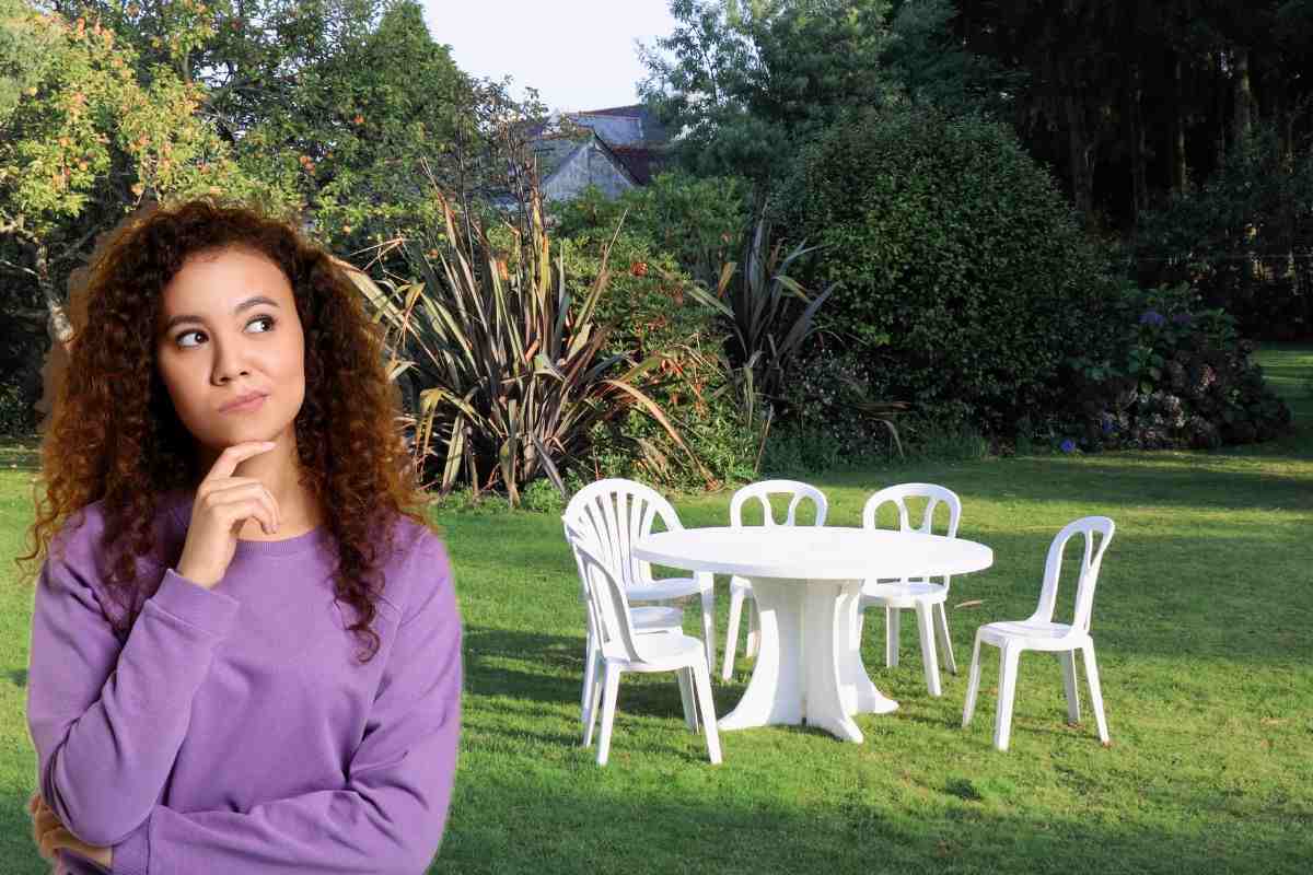 Donna che pensa e tavolo e sedie bianche che si trovano in un giardino