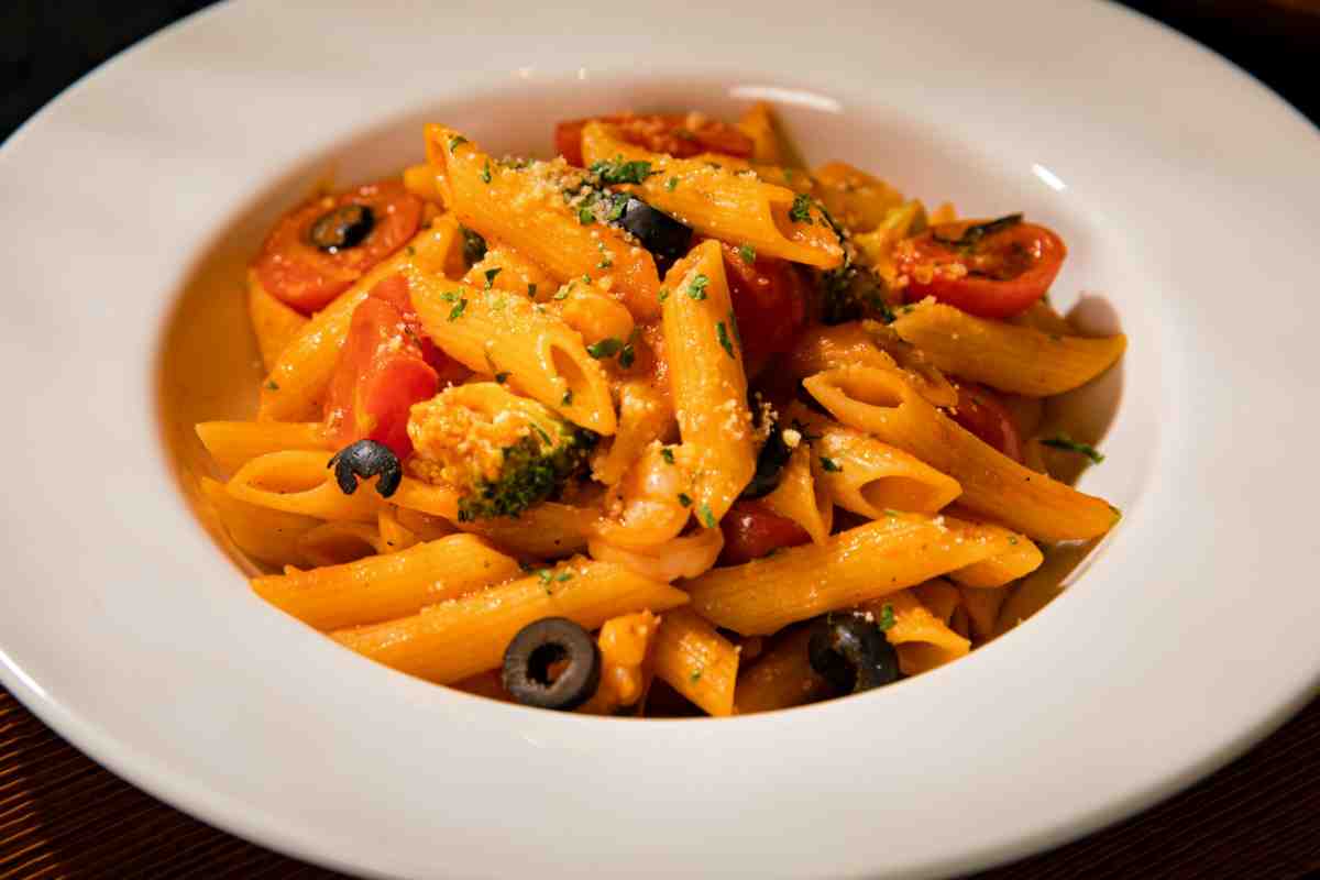 Pasta di lenticchie con pomodori confit e olive nere in un piatto fondo