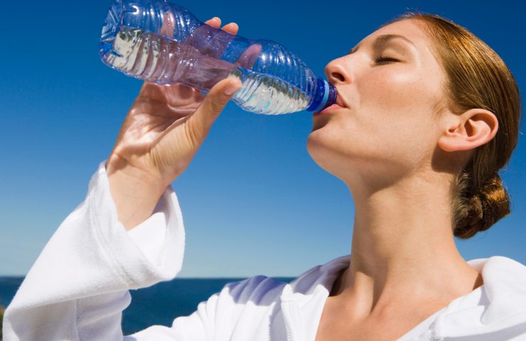 Donna che beve da una bottiglietta