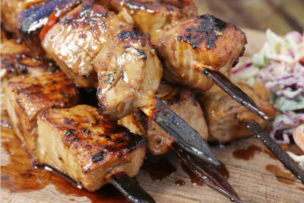 Pila di spiedini di tonno alla piastra in un piatto con salsa bbq
