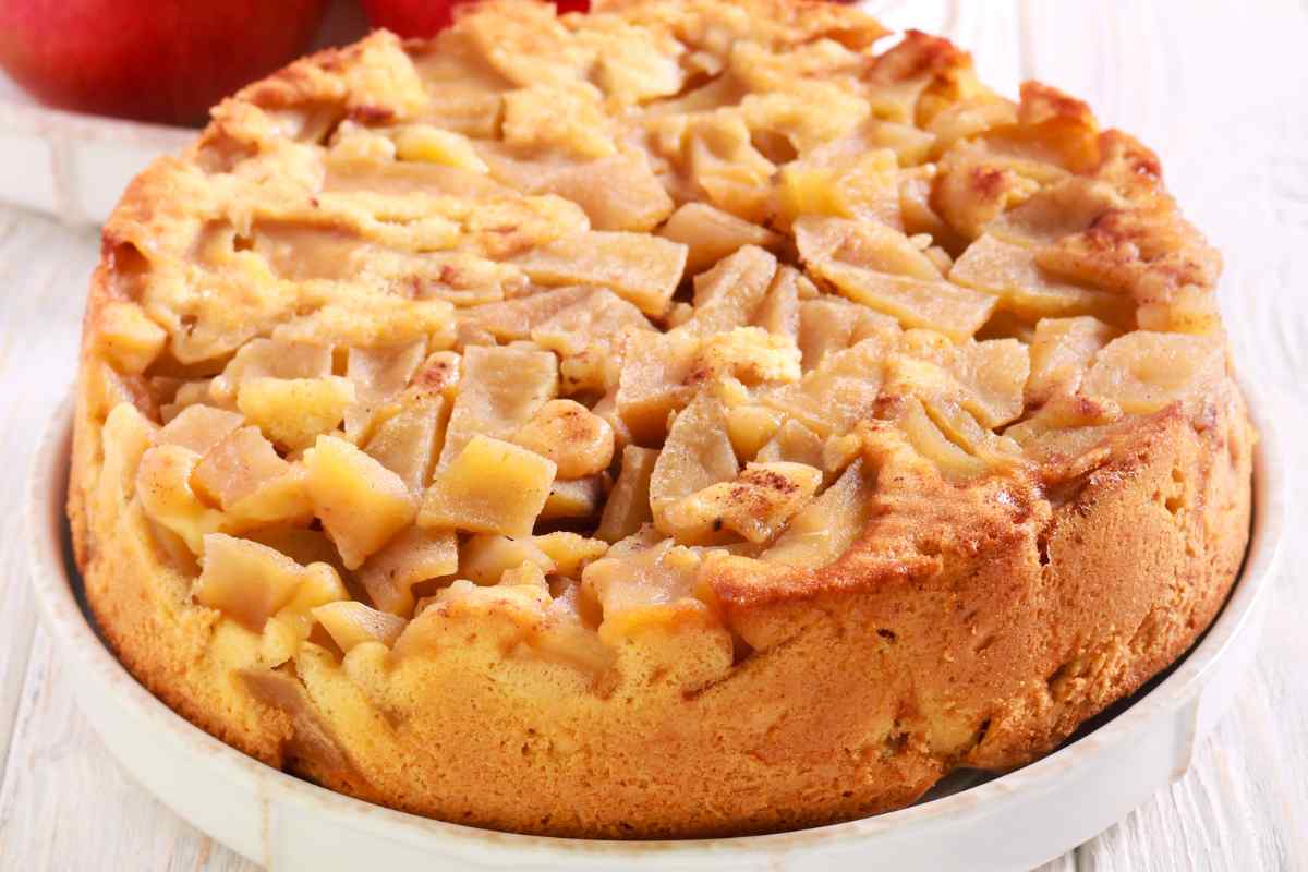 Torta di mele rovesciata senza uova e burro in un vassoio con mele rosse sullo sfondo