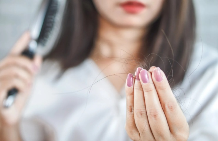 donna che tiene in mano dei capelli e nell'altra mano una spazzola