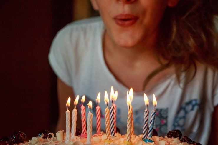 ragazza che soffia sulle candeline sopra la torta di compleanno