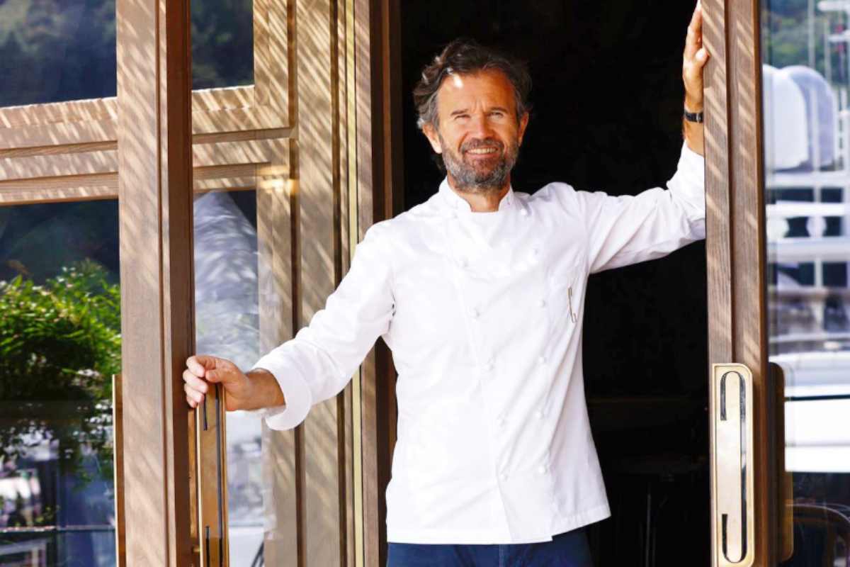 carlo cracco che sorride sulla porta di uno dei suoi ristoranti