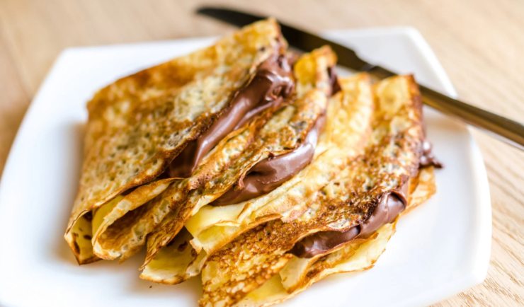 crepes farcite di crema al cioccolato su un piatto con accanto un coltello
