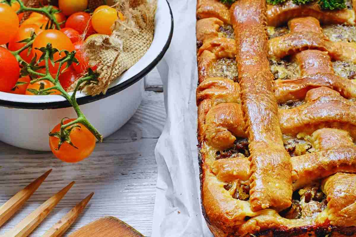 una torta rustica e dei pomodorini a fianco in una ciotola