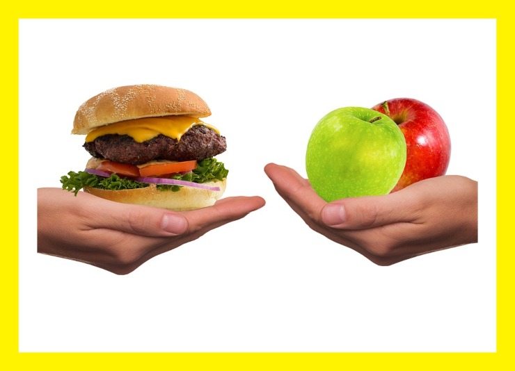hamburger e mele tenute sopra due mani una di fronte all'altra