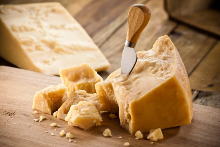 formaggio grana su un tagliere di legno e coltello per tagliarlo