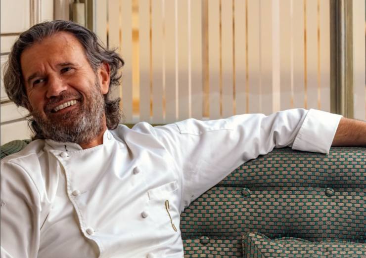 carlo cracco sorride seduto su un divano